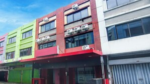 A multi-story building with air conditioning units, a green and red facade, and a closed garage door. - Hotel O Makassar near RS Grestelina formerly Wisma Makassar (Makassar)