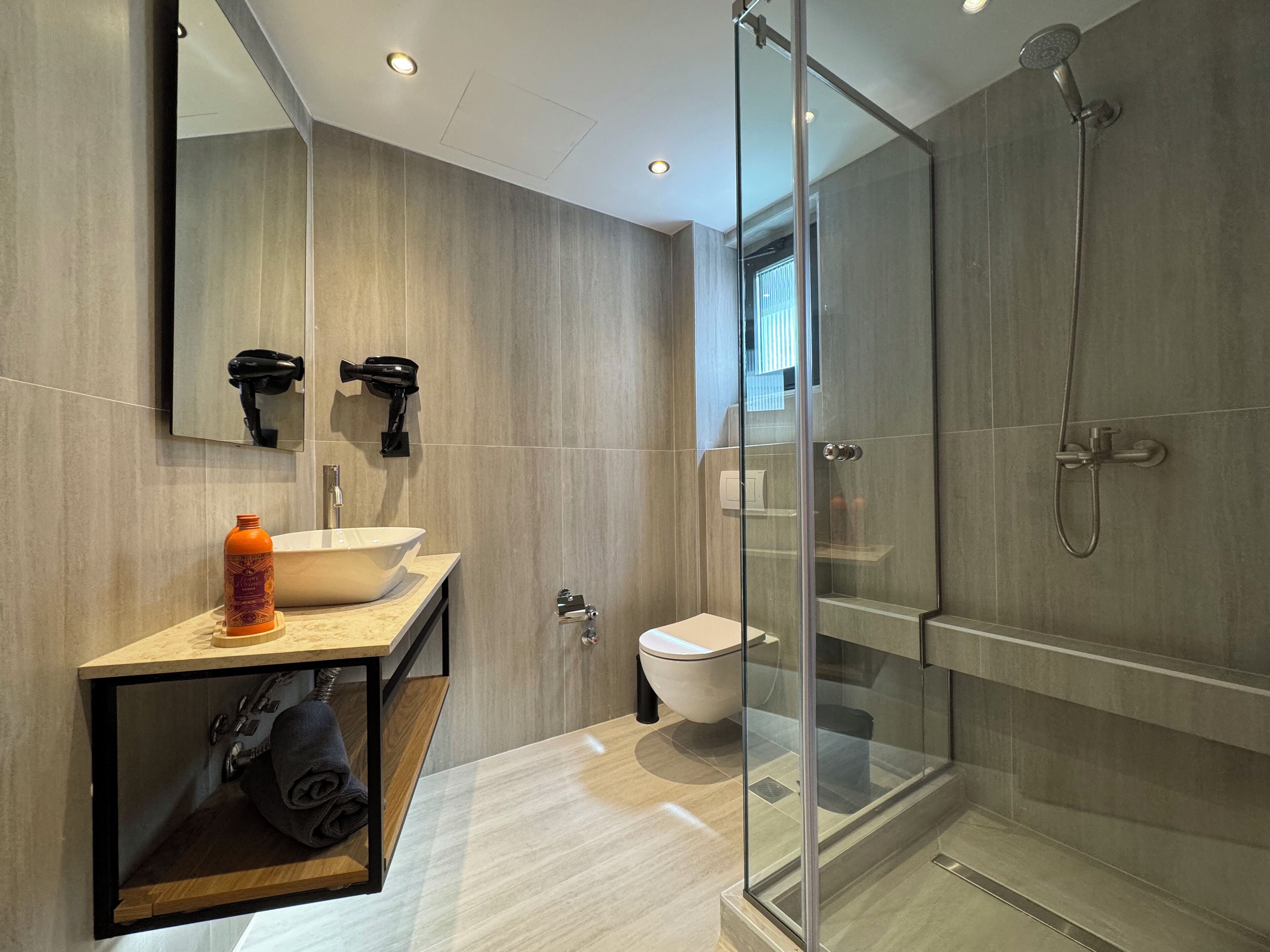 Ein modernes Badezimmer mit einer Duschkabine, einem Waschbecken mit Handtuchhalter und einer Toilette.