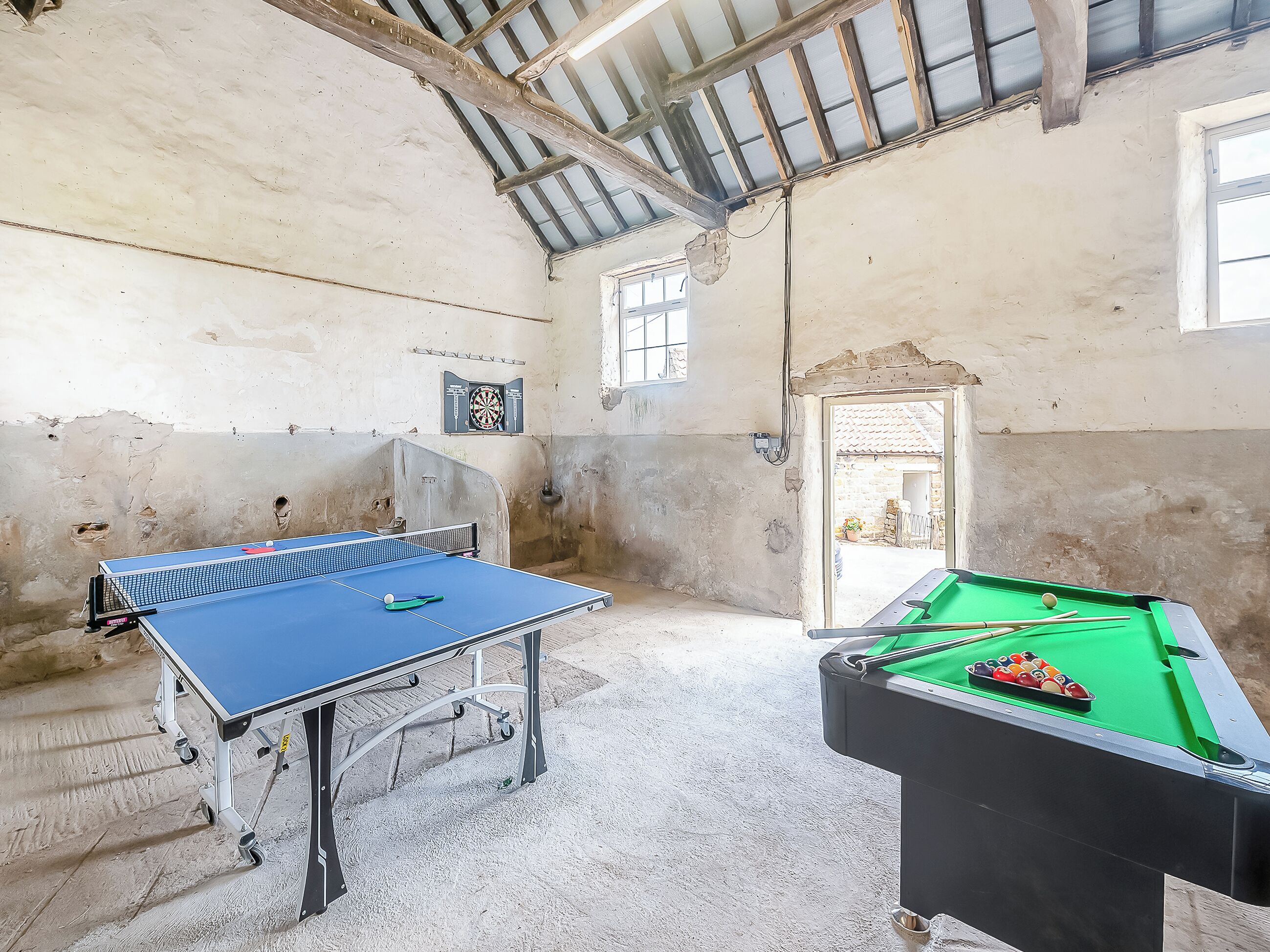 Une pièce équipée d’une table de ping-pong, d’une table de billard et d’un jeu de fléchettes.
