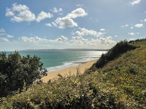 A coastal landscape with a beach, vegetation, and a clear sky.