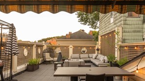 Eine überdachte Terrasse mit einem Holztisch, Korbstühlen und einer gepolsterten Sitzecke.