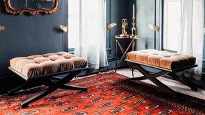 Ein Zimmer mit dunkelblauen Wänden, einem großen, verzierten Spiegel, zwei Polstersofas, einem roten Teppich mit Muster und einer Kristallleuchtre.