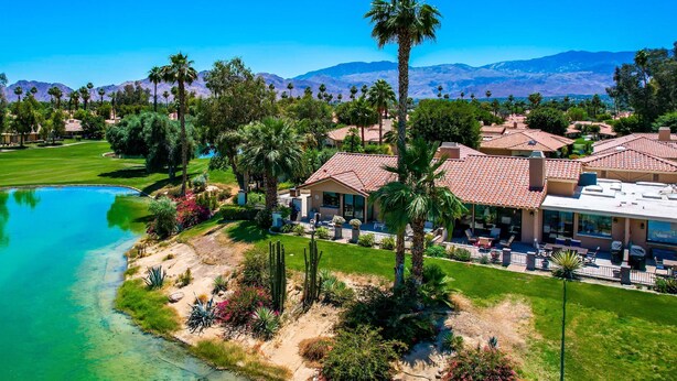 A resort with a pool, palm trees, and mountain views.