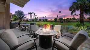 A patio with outdoor seating and a fire pit, overlooking a golf course.