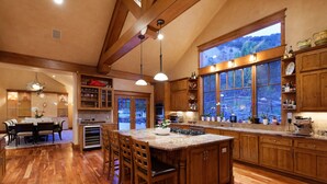 Un'ampia cucina con mobili in legno, una grande isola e vista su un paesaggio montuoso attraverso una finestra panoramica.