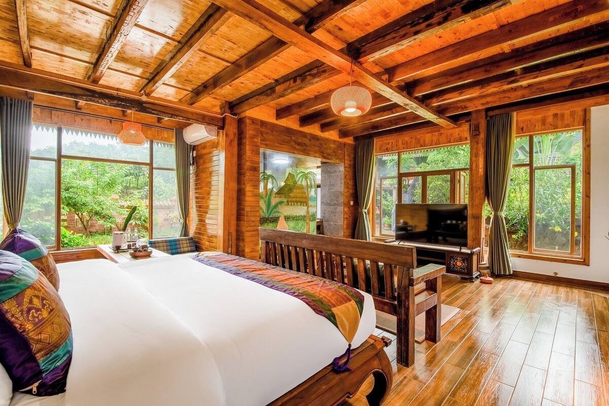 Eine Holzhütte mit einem großen Bett, einem Fernseher und einem Essbereich.