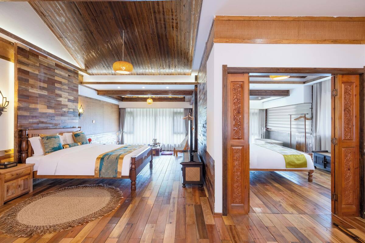 Ein geräumiges Schlafzimmer mit einem großen Bett, Holzboden und rustikaler Decke.