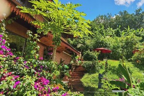 A lush garden with a wooden staircase leading to a building, surrounded by vibrant flowers and greenery. - Zhaizili Resort Xishuangbanna  (Xishuangbanna Dai)