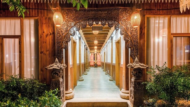 A hallway with wooden walls, decorative columns, and hanging lanterns. - Zhaizili Resort Xishuangbanna  (Xishuangbanna Dai)