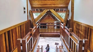 A wooden staircase with a view of a balcony and a person standing at the bottom. - Zhaizili Resort Xishuangbanna  (Xishuangbanna Dai)