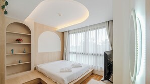 A modern bedroom with a built-in bed, a flat-screen TV, and a shelf with decorative items. - 1BR with Infinity Pool Gym Rooftop C190 (Kamala)