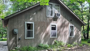 A wooden cabin with two windows, a door, and a small porch.