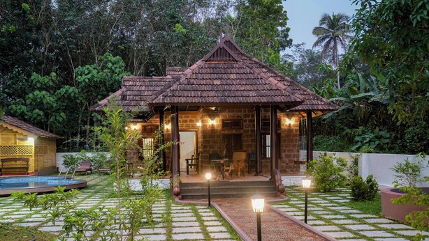 A traditional house with a tiled roof, a stone exterior, and a small pool in the foreground.