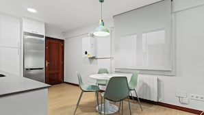 A modern kitchen with a built-in refrigerator, a dining table with chairs, and a pendant light.