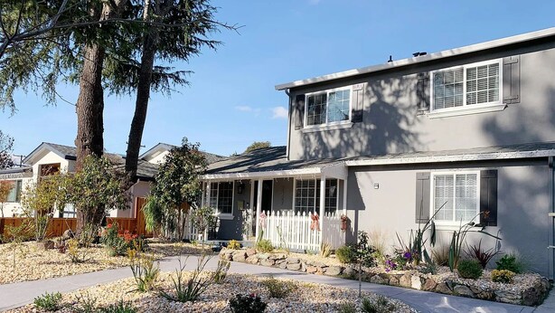 A two-story house with a covered porch, a fenced yard, and a landscaped garden with rocks and plants. - Delightful 5-bedroom house with AC in San Jose (San Jose)