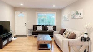 A living room with a sofa, a coffee table, a TV, and a door with a window. - Delightful 5-bedroom house with AC in San Jose (San Jose)