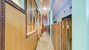 A long hallway with wooden lockers on one side and a wooden wall on the other. - Hotel O Sybilla Cafe & Homestay (Malang)