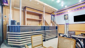 A restaurant with a counter, chairs, and a staircase. - Hotel O Sybilla Cafe & Homestay (Malang)