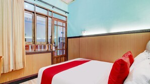 A hotel room with a bed, a window with curtains, and a wooden headboard. - Hotel O Sybilla Cafe & Homestay (Malang)
