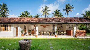 A house with a tiled roof, outdoor seating area, and a well-maintained lawn. - SAMA Ahangama (Ahangama)