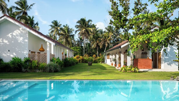 A poolside view of a resort with a clear blue pool, white buildings, and lush tropical vegetation. - SAMA Ahangama (Ahangama)