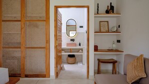 A room with a wooden sliding door, a mirror, a small stool, a bench, and a sofa. - SAMA Ahangama (Ahangama)