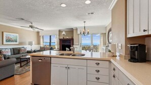 Una cocina moderna con una isla central, un comedor con vistas y una sala de estar con sofá y un cuadro.