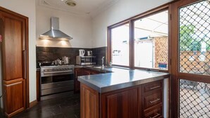 A modern kitchen with dark wood cabinets, stainless steel appliances, and a large island. - Bunbury Bliss - Views and Vibes (East Bunbury)