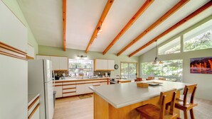 Une cuisine moderne avec des poutres en bois, un grand îlot central et beaucoup de lumière naturelle.