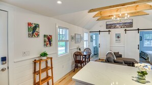 Una cocina moderna con armarios blancos, una isla de madera y un comedor con mesa y sillas.