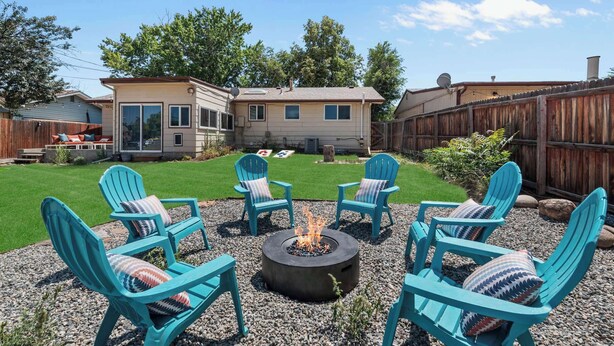 Un jardin avec un foyer et quatre chaises Adirondack turquoise.