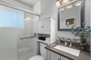 Une salle de bain moderne avec une douche à parois de verre, un meuble-lavabo blanc et un miroir au-dessus du meuble.