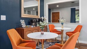 Un espace repas moderne avec des chaises orange, une table ronde et une machine à café.