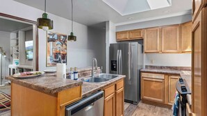 Une cuisine moderne avec des meubles en bois, un réfrigérateur en acier inoxydable, un lave-vaisselle et un plan de travail en granit.