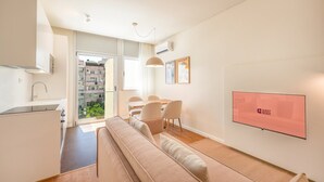 A modern apartment with a kitchenette, dining area, and a large window overlooking a residential area.