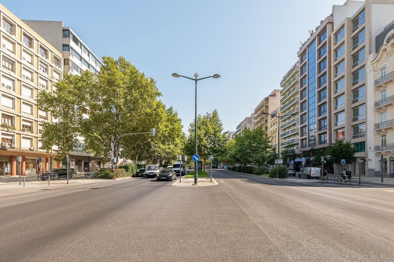 Une rue bordée d’immeubles modernes, un ciel dégagé et un passage piéton.