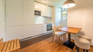 Una cocina moderna con armarios blancos, una mesa de comedor de madera y un horno empotrado.