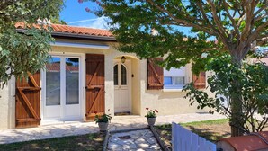 A house with a tiled roof, a white door, and wooden shutters. There are potted plants in front of the house. - Family home in Fouras - enclosed garden near beach and market  (Fouras)
