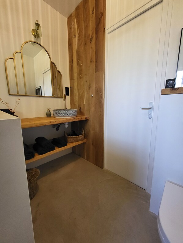 A bathroom with a wooden vanity, a large mirror, and a white door.