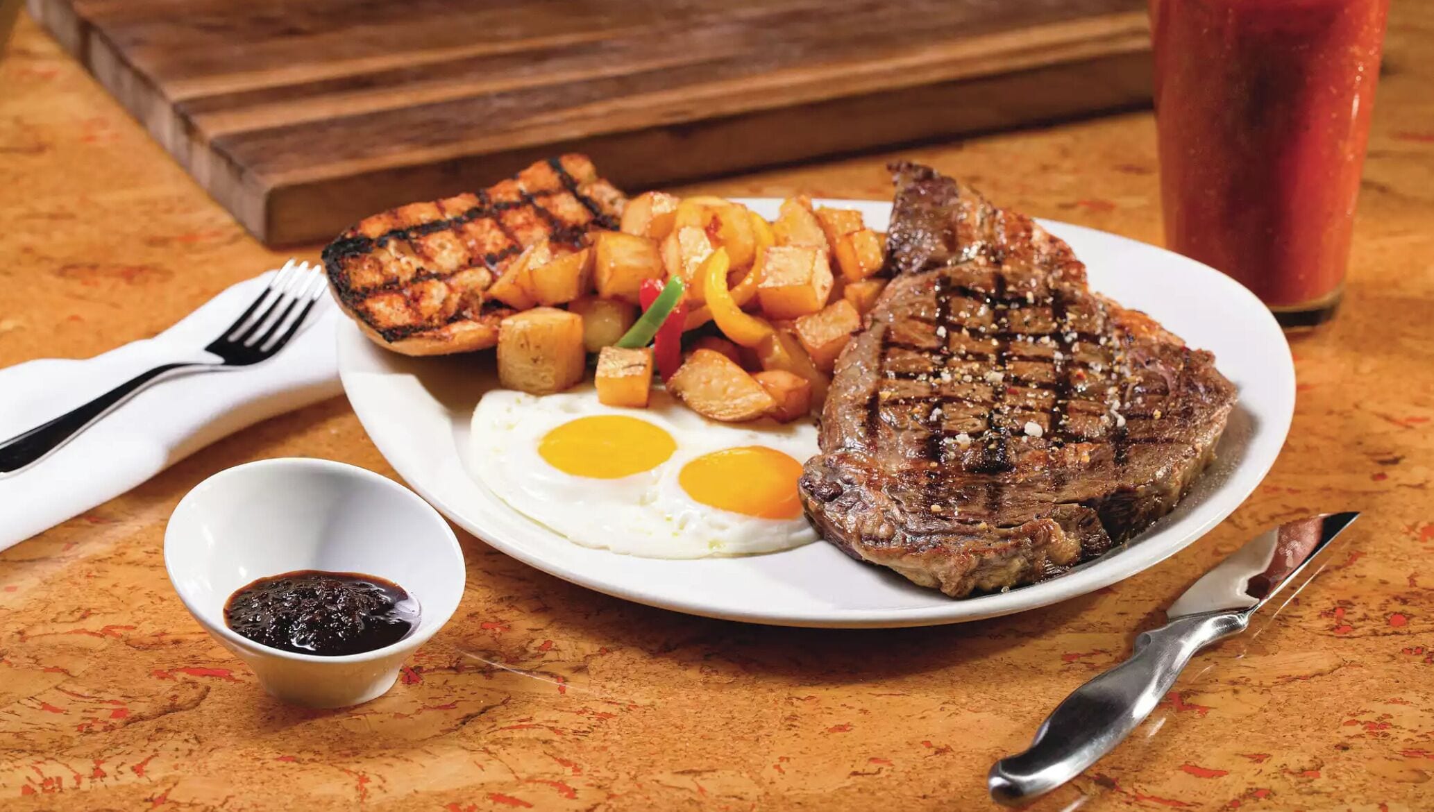 Ein Teller mit gegrilltem Steak, Spiegeleiern und Bratkartoffeln.