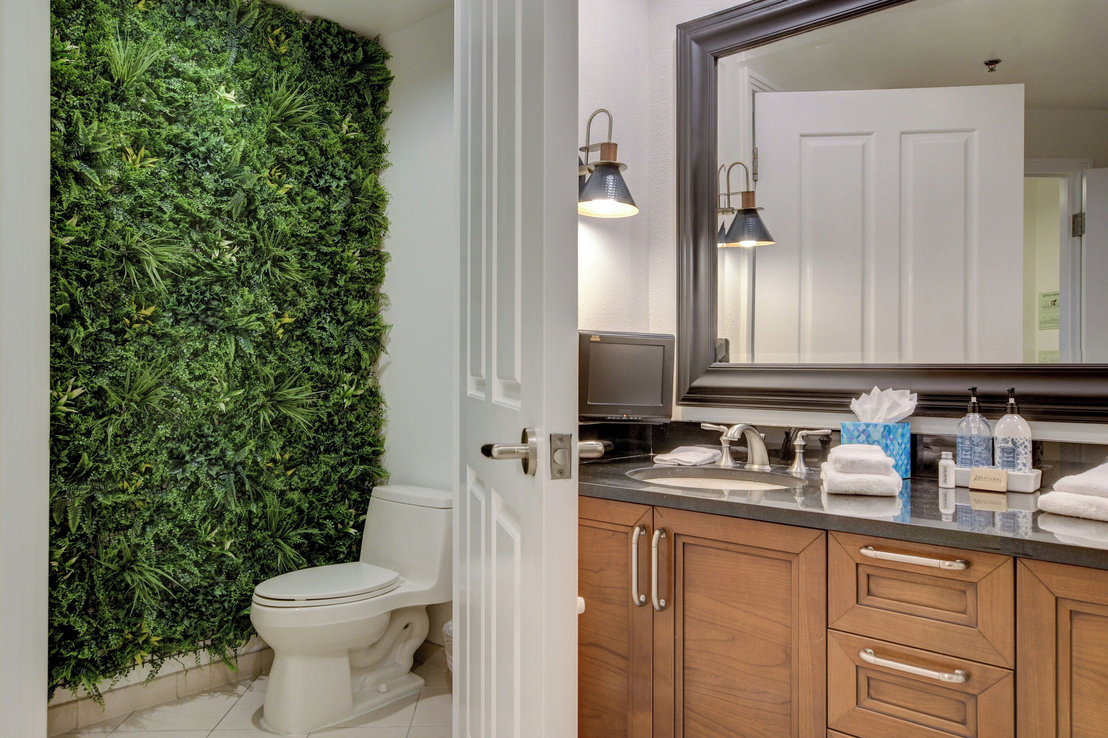 A bathroom with a green wall, white toilet, wooden cabinets, and a mirror.