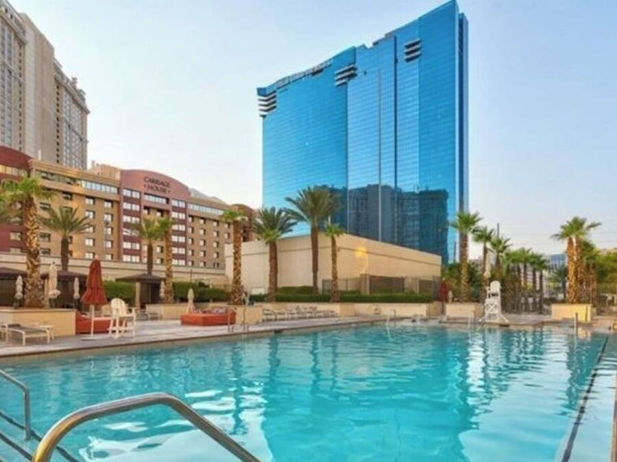 Un hotel con piscina, palmeras y edificios modernos al fondo.