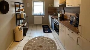 A compact kitchen with white cabinets, a window, and a decorative rug.