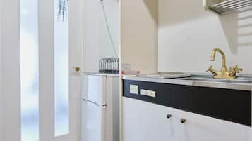 A kitchen with a stainless steel sink, a refrigerator, and a window with frosted glass.
