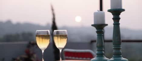 Two glasses of white wine on a wooden table with a candle and candle holder in the background.