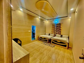 Ein Zimmer mit zwei Betten, einem Deckenventilator und einem kleinen Schreibtisch.
