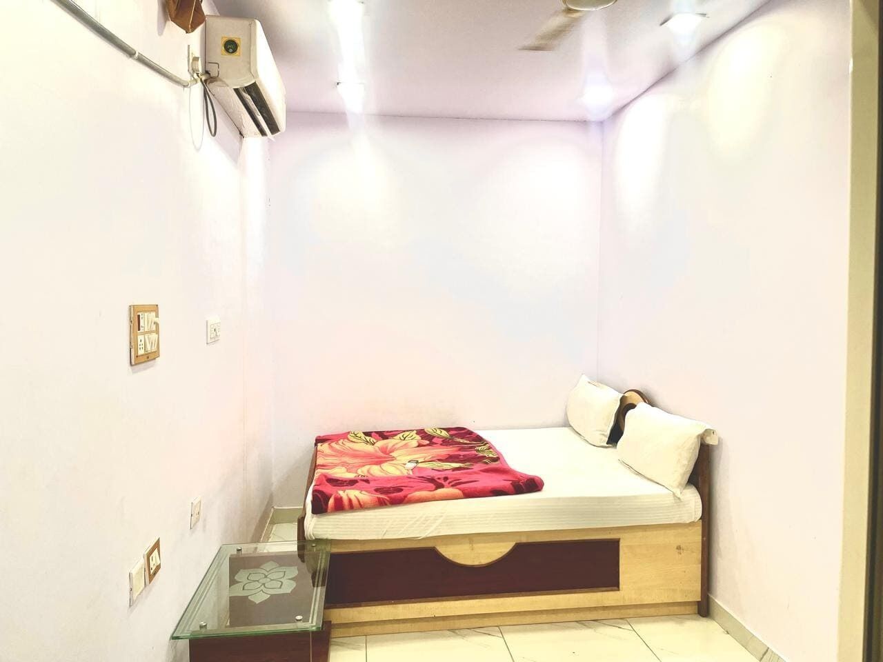 Un dormitorio pequeño y bien iluminado con una cama individual, una mesita de noche y un ventilador de techo.