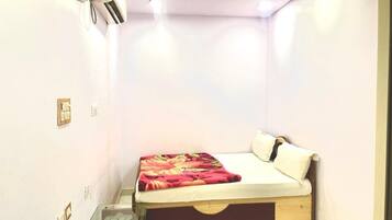 Un dormitorio pequeño y bien iluminado con una cama individual, una mesita de noche y un ventilador de techo.
