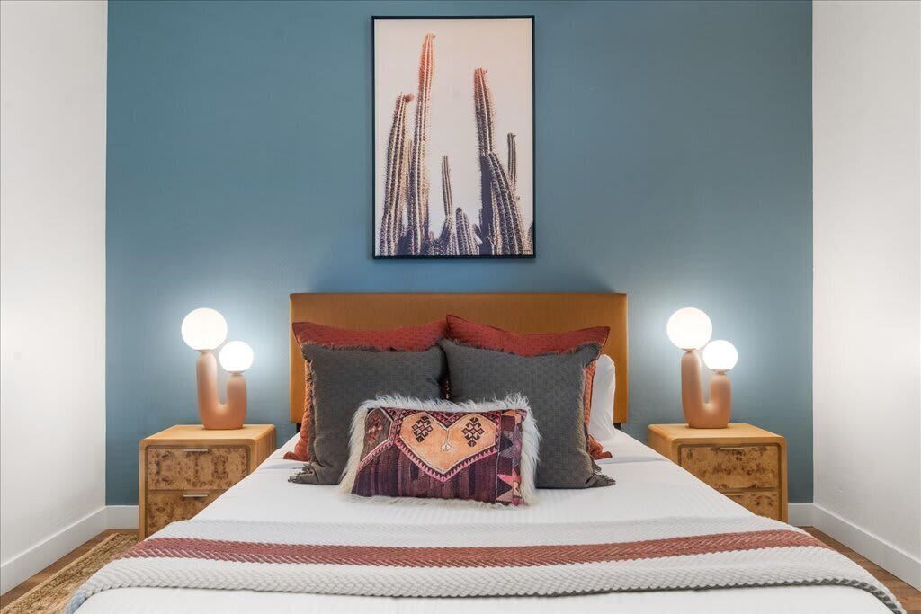 Een slaapkamer met een bed, twee nachtkastjes, een wandlamp en een foto in een lijst.