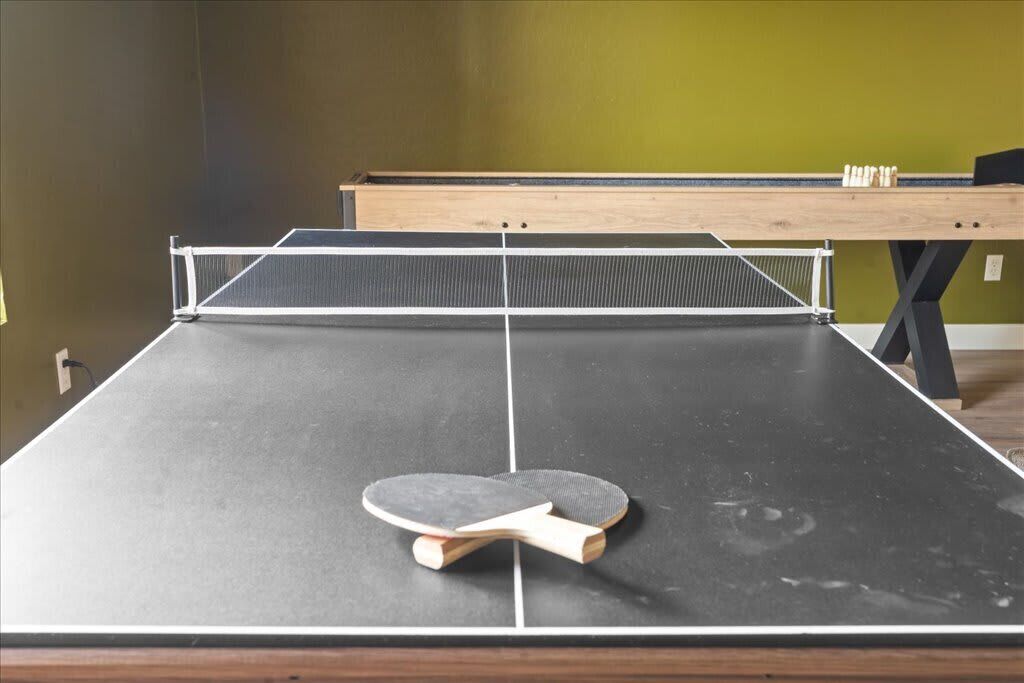 A ping pong table with a net in a room with green walls and a wooden table in the background.